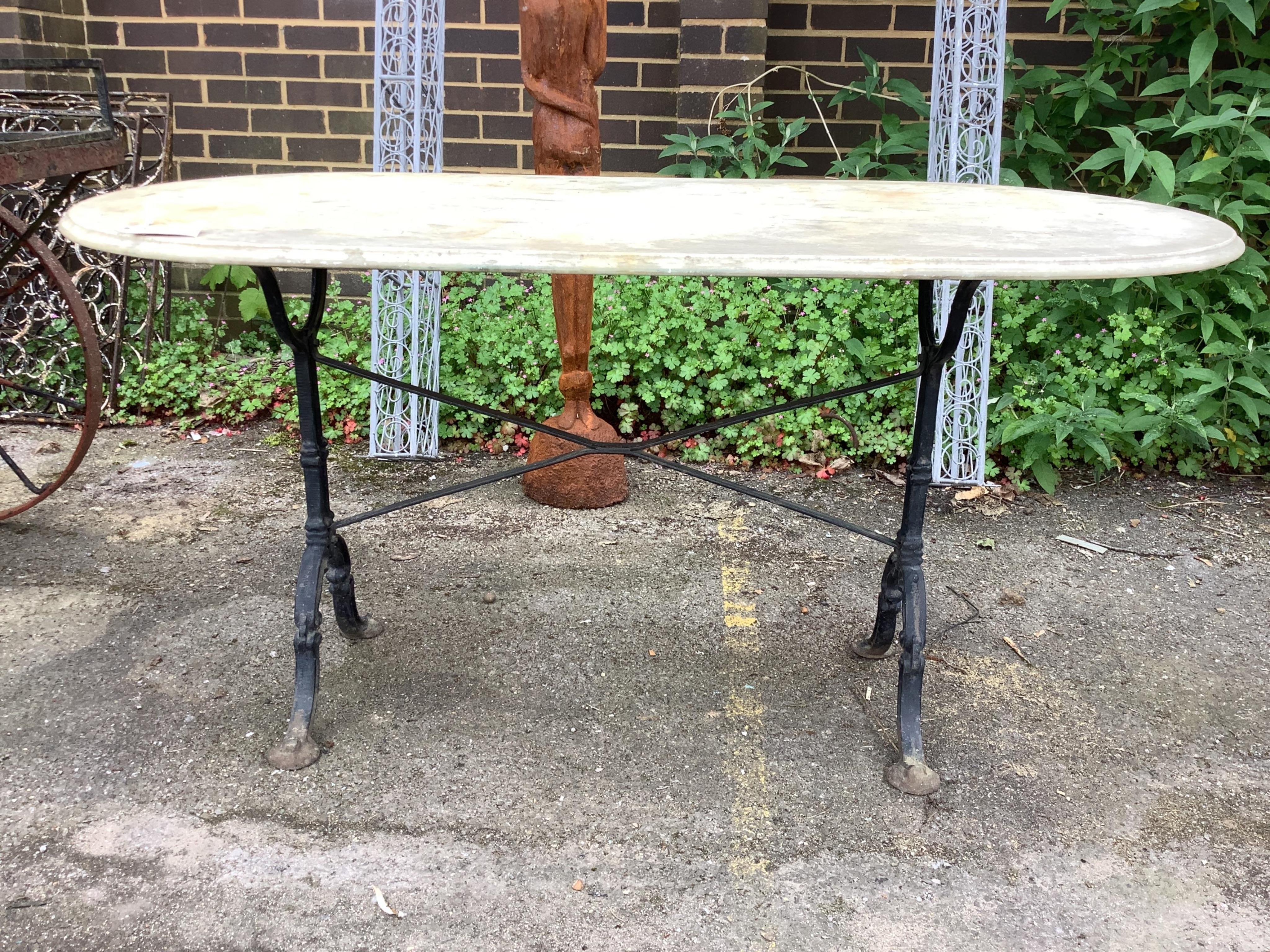An oval reconstituted marble and wrought iron garden table, width 135cm, depth 69cm, height 70cm